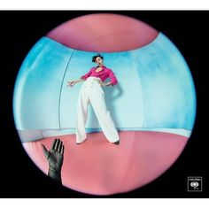 a woman in pink shirt and white pants standing on top of a blue ball with her hands out