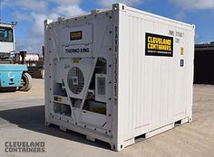 a white container sitting in the middle of a parking lot next to a forklift