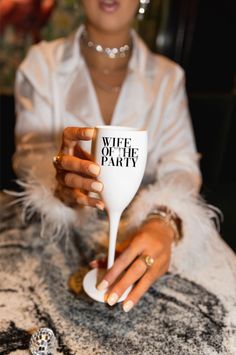 a woman holding a white wine glass with the words wife of the party on it