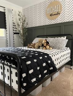 a teddy bear sitting on top of a black and white bed