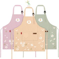 three aprons with daisies on them, one is pink and the other is green