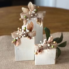 two white vases decorated with flowers and burlocks on top of a table