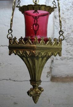 a red candle is hanging from a brass chandelier