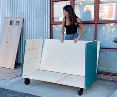 a woman standing next to a couch made out of plywood