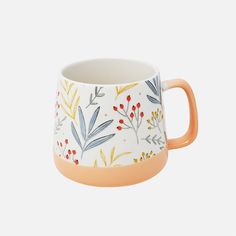 an orange and white coffee mug with floral designs on the outside, sitting in front of a white background