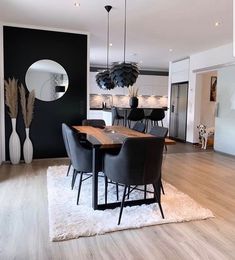 a modern dining room with black walls and white rugs on the wooden flooring