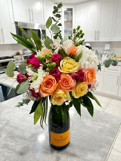 a vase filled with lots of colorful flowers on top of a kitchen counter next to an oven