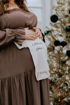 a woman in a brown dress is holding a white shirt with writing on it that says, happy holidays