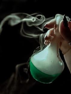 a hand holding a flask filled with liquid and steam rising from it's top