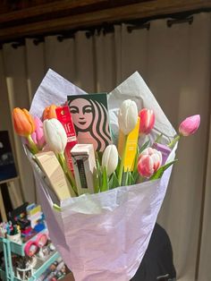 a bouquet of flowers in a paper bag with starbucks coffee and lip care products on it