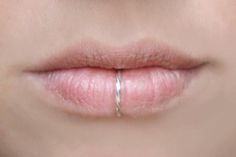 a woman's lips with a ring on the tip of her lip in front of her face