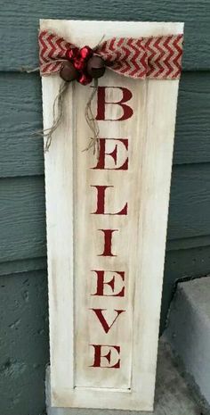 a sign that says believe hanging on the side of a house in front of a door