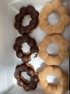 four donuts in a white box with chocolate frosting and sprinkles