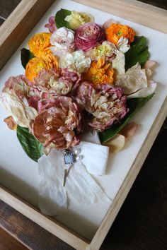 a bouquet of flowers sitting in a wooden box on top of a table with the words diy wedding bouquet presentation