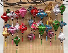 a bunch of balloons are hanging from a tree branch in front of a bamboo mat