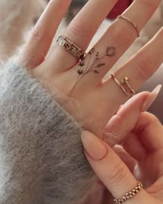 a woman's hand with four different rings on it