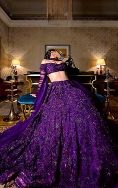 a woman in a purple dress is standing near a table with candles and chandelier