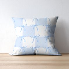 a blue and white checkered pillow with bows on it sitting on a wooden table