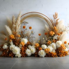 an arrangement of white and orange flowers in front of a brick wall with a circular frame