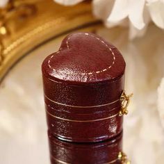 a close up of a small wooden box on a table with flowers in the background