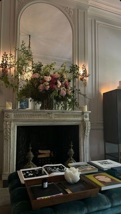 a living room filled with furniture and flowers on top of a fireplace mantel in front of a mirror