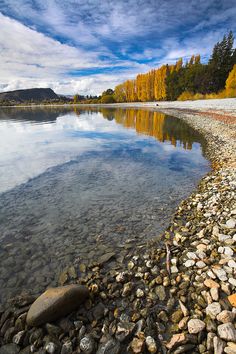 the water is crystal clear and there are many rocks on the shore near the lake