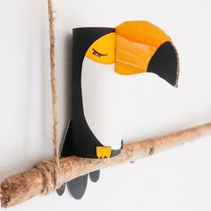 a toucan hanging from a rope on the wall next to a piece of wood