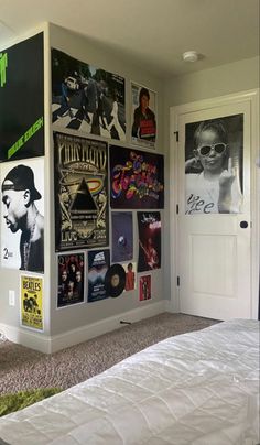 a bedroom with posters on the wall and a bed in front of it, next to a doorway