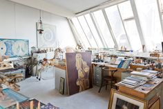 an artist's studio with lots of art work on the walls and desks