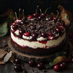 a cake with cherries and chocolate shavings on it sitting on a wooden table