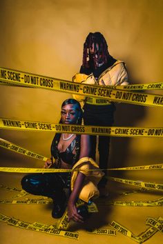 two people sitting on the ground surrounded by caution tape