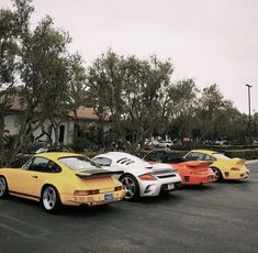 three porsches parked in a parking lot next to trees and bushes on a cloudy day