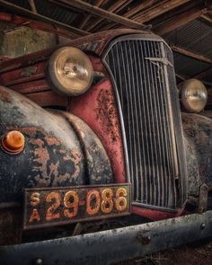 an old rusted out car is sitting in the garage with its license plate on