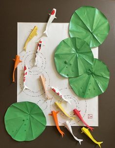 paper plates with fish and umbrellas on top of a piece of paper that is cut out to look like waterlilies