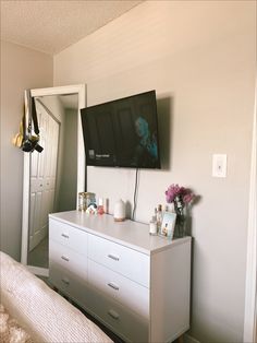 a flat screen tv sitting on top of a white dresser