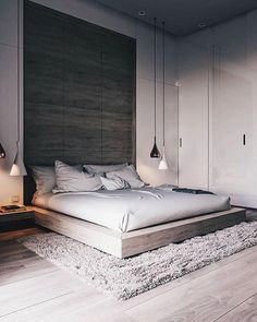 a large bed sitting on top of a wooden floor next to a wall mounted light