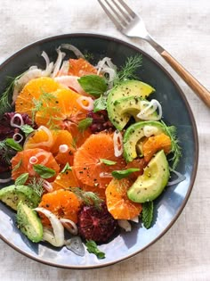 a salad with oranges, avocado and cranberries in a bowl