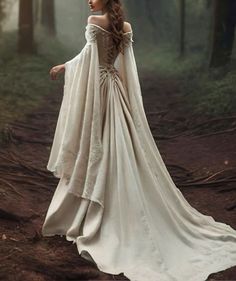 a woman in a white dress is walking through the woods