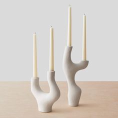 three white candles sitting on top of a table next to each other with one candle in the middle