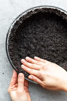 someone holding their hand over the top of a pot filled with dirt and water,