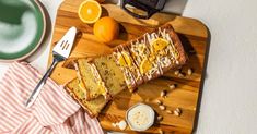 a wooden cutting board topped with slices of cake next to an orange and coffee cup