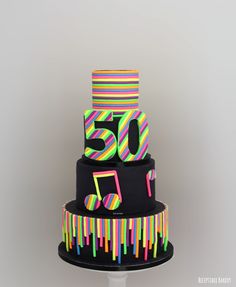 a multi - tiered cake decorated with colorful icing and music notes on top