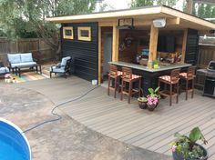 a backyard bar with chairs and tables next to a swimming pool in the back yard