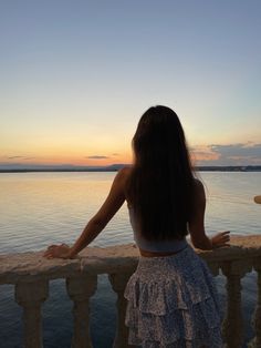 a woman looking out over the water at sunset