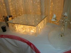 a table topped with a glass box next to a candle holder