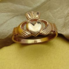 a gold clad clad heart ring on top of a yellow cloth with a white diamond in the middle