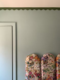 three colorfully decorated chairs in front of a mirror on a wall with scalloped trim