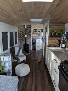 a kitchen and living room in a tiny home with wood flooring, white cabinets and appliances