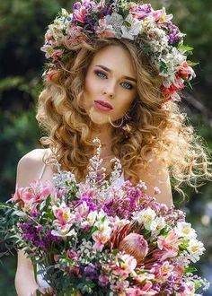 a beautiful woman holding a bouquet of flowers in her hands and looking at the camera