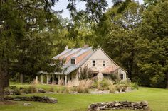 a stone house surrounded by trees and grass